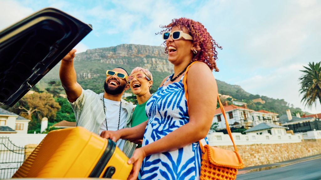 Happy people loading luggage in a car on vacation.