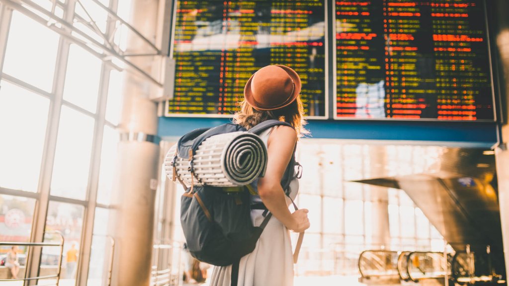 Woman with luggage reads travel schedule.