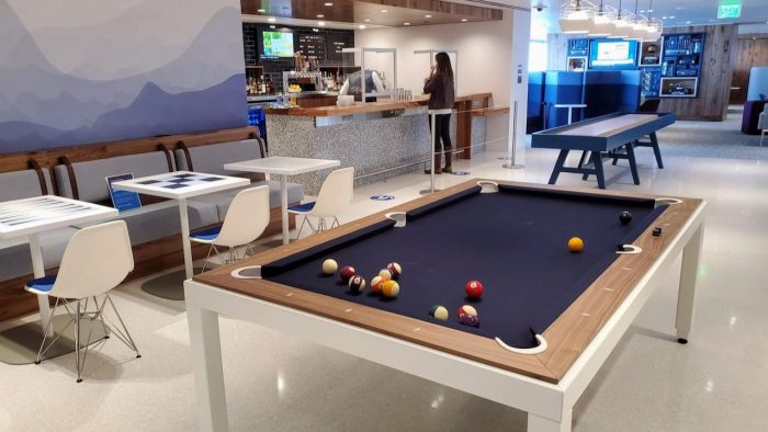 A pool table in use at the Denver Amex Centurion Lounge with a bar and seating in the background.