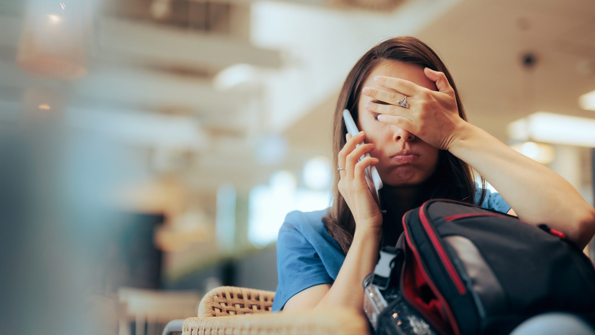 Stressed traveler speaking on her cellphone feeling overwhelmed.