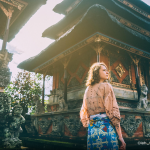 A young female tourist gazes thoughtfully in front of a Balinese temple in Indonesia.