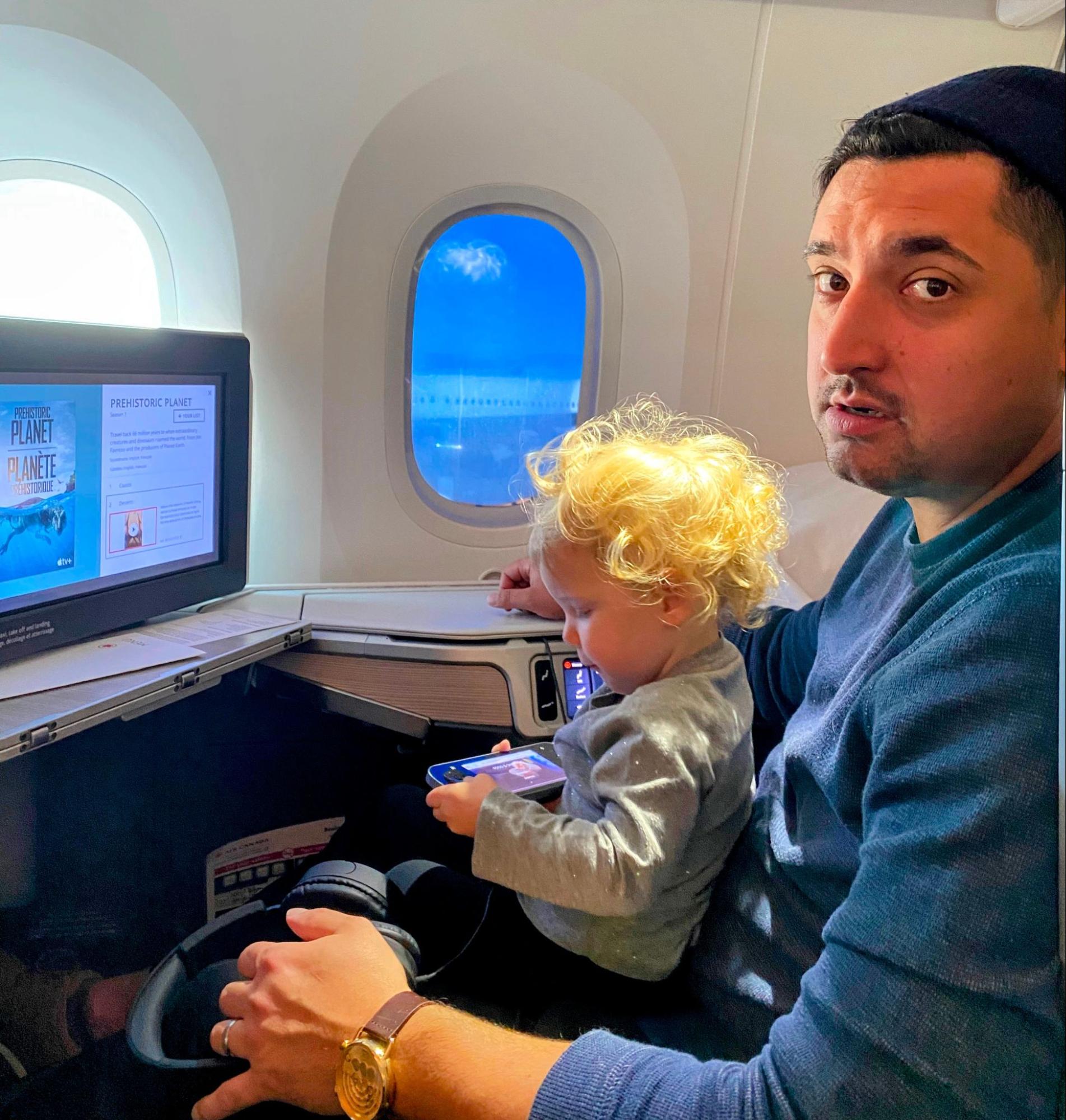 Author Joseph Hostetler and his toddler child sitting in Qatar Airways Qsuites business class.