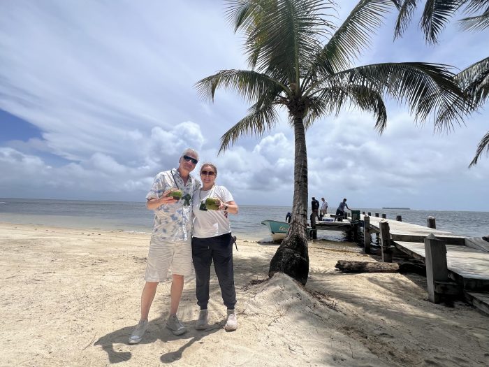 Photo of writer Adam Frankel and his wife standing on the beach holding coconut drinks at the Calala Island Resort in Nicaragua.